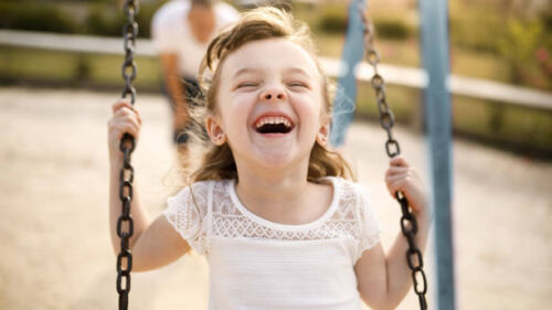 Smiling girl playing on the swing.