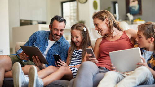 Shot of a happy young family using wireless devices on the sofa at home