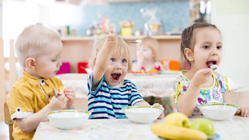 funny kids group eating in kindergarten